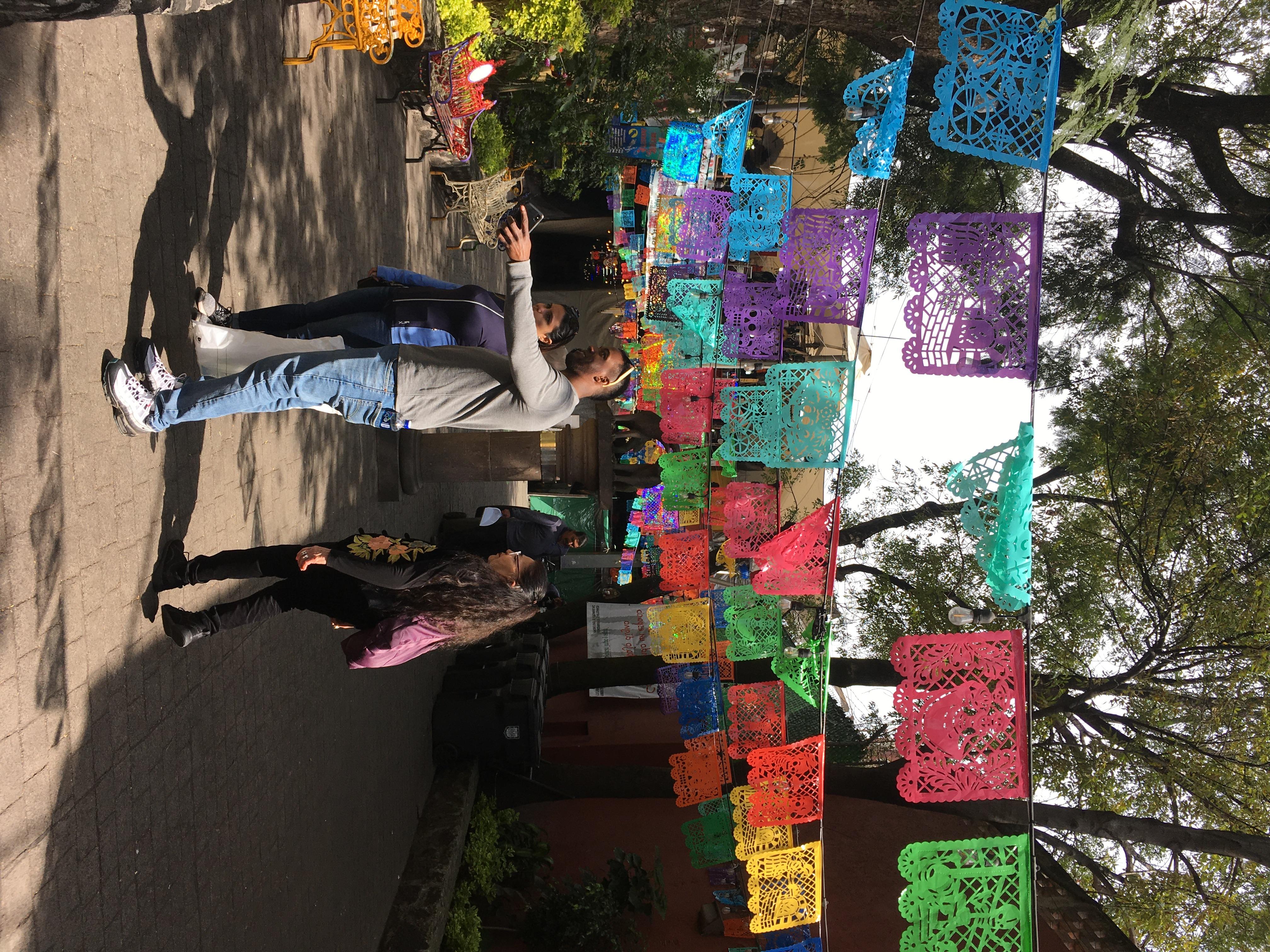 people stand together underneth garlands of paper cut in traditional mexican style